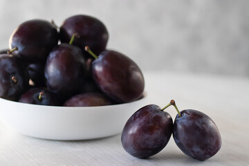Ripe organic plums in a white bowl.