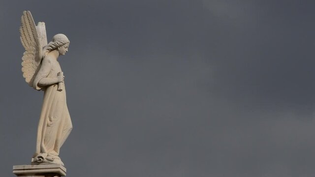 Stone statue with the figure of a angel on a grave in a cemetery a cloudy day