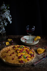 Tart with orange cream. Decorated with pomegranate and mint leaves on a warm wooden background.