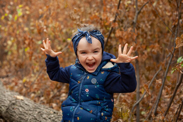 Little girl grimaces at the camera. The girl is alone in the forest.