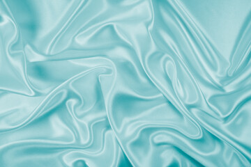 Obraz premium Photography of beautiful wavy turquoise silk satin luxury cloth fabric, abstract background design.