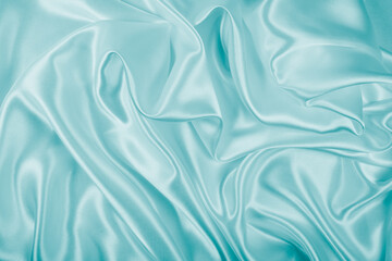 Photography of beautiful wavy turquoise silk satin luxury cloth fabric, abstract background design.