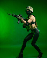 Obraz na płótnie Canvas woman in military uniform with an American automatic rifle in a helmet and Balaclava on a green background