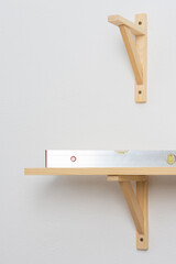The process of fixing the wooden shelf to the wall, the level tool checks the evenness of the shelf