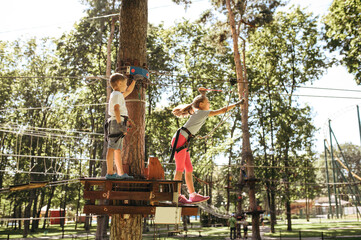 Little funny kids climbs on net in rope park