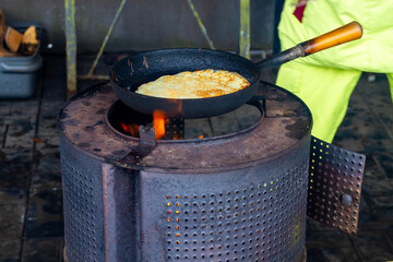 Oven, fry pancakes in a cast-iron black pan. Cooking pancakes on an open fire on an iron stove in...