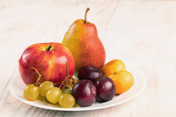 Assorted fruits plate with fruit on wooden table Autumn harvest