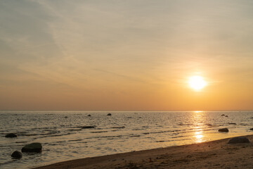 Fototapeta na wymiar Sunset on baltic sea beach with rocks in sand