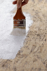 Half painted natural wood surface in white with paint brush