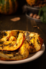 Baked pumpkin in a plate, pieces of pumpkin with dill and parsley, spices and lemon juice baked in foil in the oven