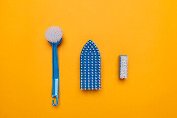  blue brushes for washing clothes and toilet bowl on a yellow background.
