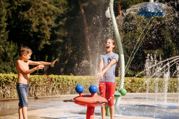 Boy and girl play with splashe, water playground - Powered by Adobe