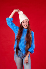beautiful girl in a sweater and a hat on a red background.