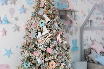 Xmas decor children room. Closeup Christmas tree decorated with toys, balls and lights garlands in home. Xmas interior of living room with decorated Christmas tree and wooden bed in shape of house. 