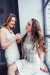 Naklejka premium two pretty twin sister blond curly hairstyle girl in luxury house interior together, rich young people concept