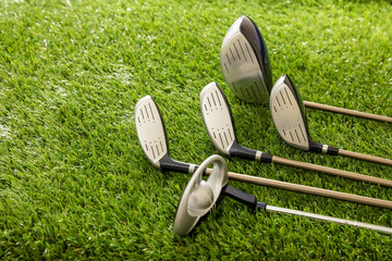 Golf clubs on green grass golf course, close up view.