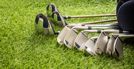 Golf clubs on green grass golf course, close up view.