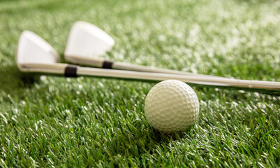 Golf ball and sticks on green grass golf course, close up view.