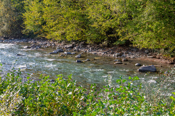 Strong water flow of a mountain river near a rocky shore