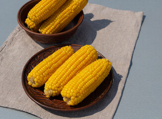 Boiled corn on an earthenware plate, closeup, selective focus. Rustic still life.