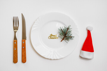 Traditional Christmas table place setting with empty white plate, linen napkin, cutlery with festive decorations. New Years background and Holiday concept. Flat lay, top view with copy space
