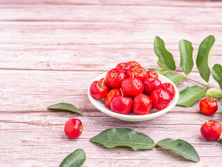 Ripe red cherries in a ceramic dish with leaves on wooden table. Space for text. Sweet organic berries. Concept of healthy fruits