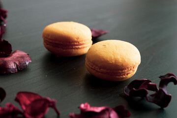 Close-up of breakfast morning with yellow macaroons lemon taste. close-up of french dessert on the black background and flowers around in a simple vintage composition. Food photography