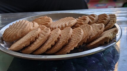 Rectangular shortbread cookies and biscuits in a steel plate on a wooden table. Round shape biscuits with line design