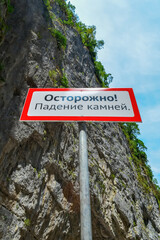 Warning sign in the mountains about the rockfall. Translation from Russian: Caution Falling stones