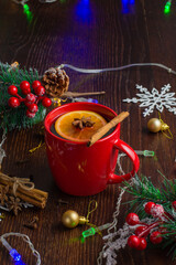 Delicious warm mulled wine with cinnamon, star anise and orange in a red cup on christmas background, vertical frame format