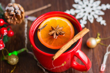 Delicious warm mulled wine with cinnamon, star anise and orange in red cup close-up on christmas background with copy space