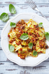 Ravioli with mushrooms and fresh basil. Bright wooden background. Top view.	