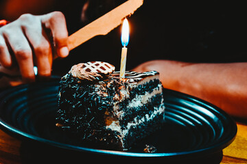 Close up shot of young woman hand cutting birthday cake with knife in restaurant