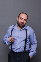 Armenian man with beard and braces smokes on gray background