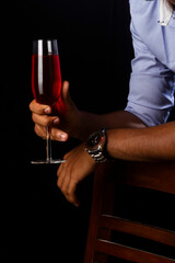 A glass of red wine with a fireplace. Hand holding glass.