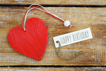 Happy birthday card with red wooden heart on rustic wood
