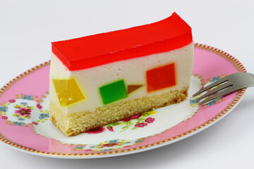 Slice of cheesecake with colorful pieces of fruit jelly pieces, closeup
