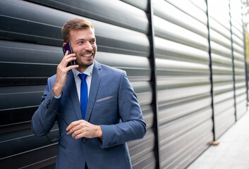 Young businessman talking on the phone in front of the modern building