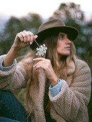 Girl in the woods wearing denim overalls and a cowboy fedora hat. Autumn vives.