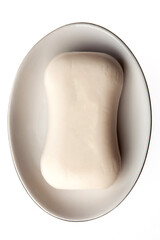 A bar of natural white soap in a soap plate isolated on white background. Studio shot. Hygiene theme - bacteria and virus prevention