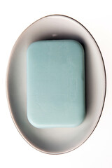 A bar of natural blue soap in a soap plate isolated on white background. Studio shot. Hygiene theme - bacteria and virus prevention