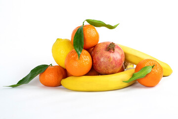 Delicious appetizing fruits - bananas, tangerines, pomegranates, lemons on a light background. Fruits are good for the human body, saturate with vitamins and fiber