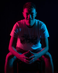 Handsome guy posing in studio on black background. Isolated with blue and red color gel