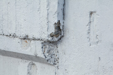 Part of a close-up concrete wall with cracks, covered with white paint. Urban texture.