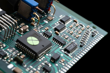 Fototapeta premium Green electronic circuit board with many electrical components against, isolated on black background