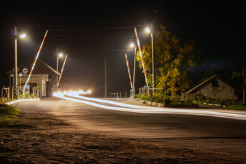 Night railway crossing with passing cars