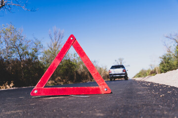 Red emergency stop sign close up on the road against the background of a broken car
