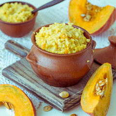 Millet porridge with pumpkin in a small clay pot on an old table. Selective focus. Tinted photo.