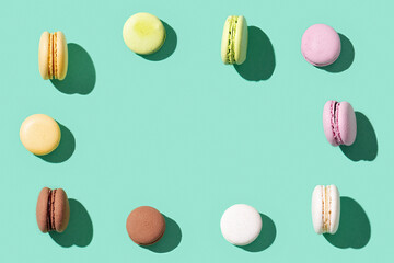 Frame from Assorted macaroons on bright blue green colored background, colorful french cookies macarons.