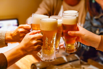居酒屋で乾杯する大勢の人の手とジョッキビール